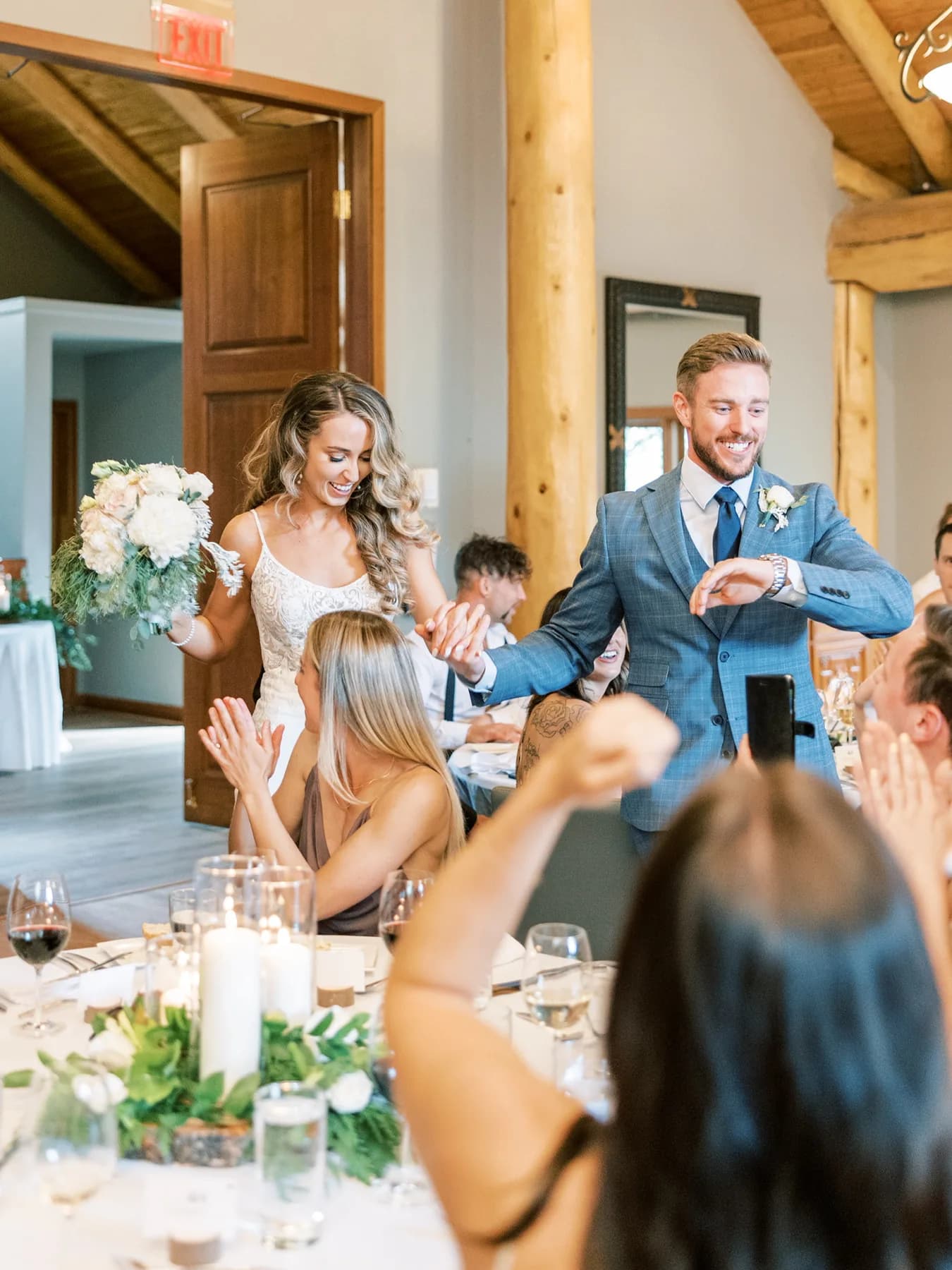 A groom in a blue suit celebrating at his wedding reception