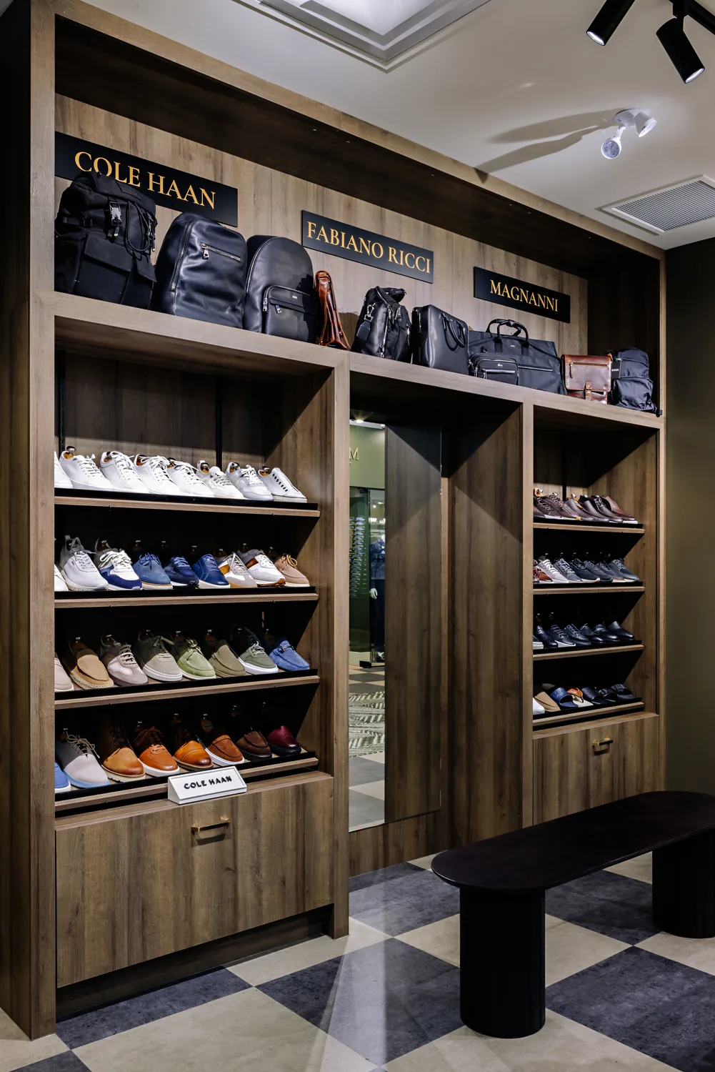 Footwear on open shelving beneath Cole Haan and Emanuel Berg signage