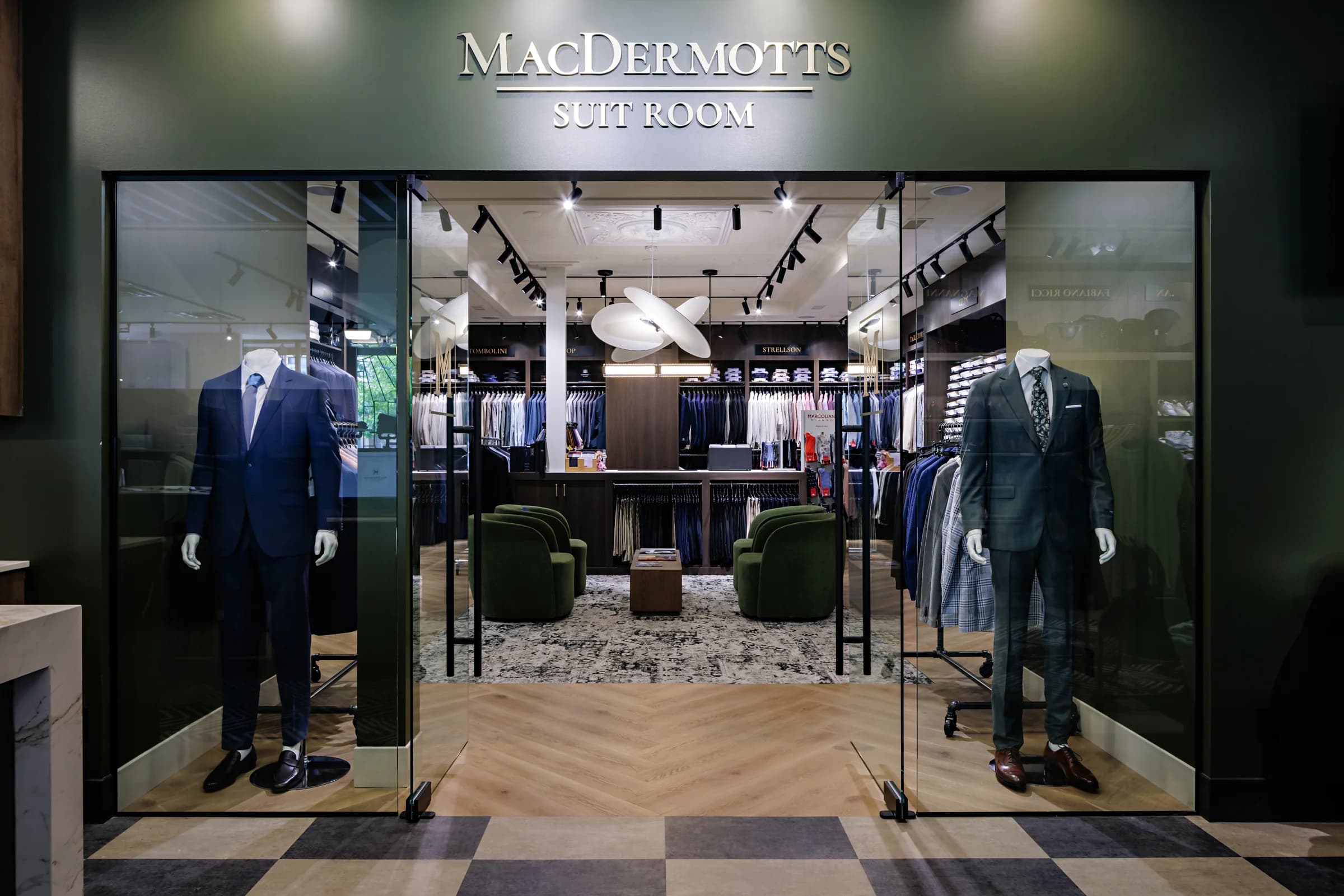 Two mannequins in suits flanking the glass entrance to the MacDermott's Suit Room